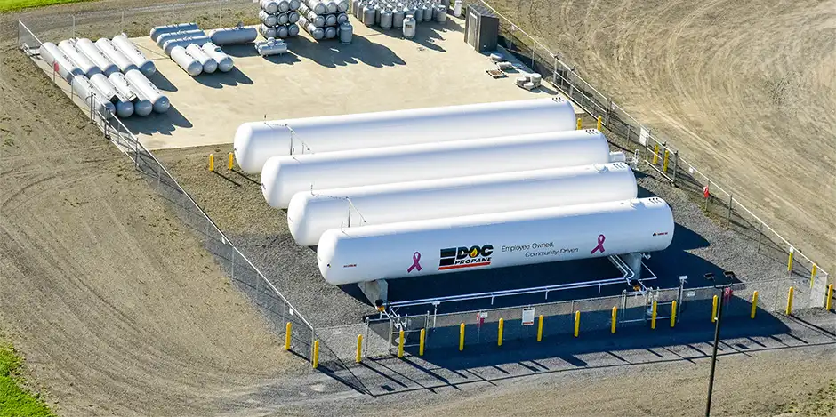 row of propane tanks in a dirt field surrounded by a chain link fence