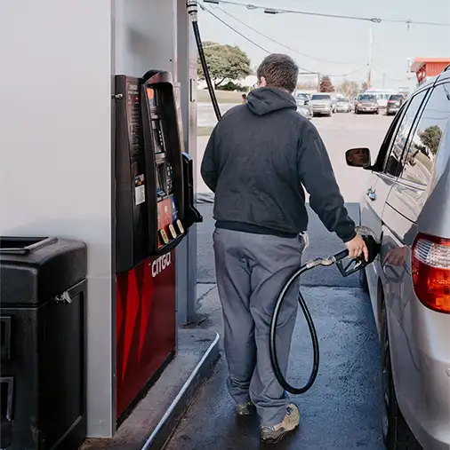 man filling up his van gas tank at a standard gas station