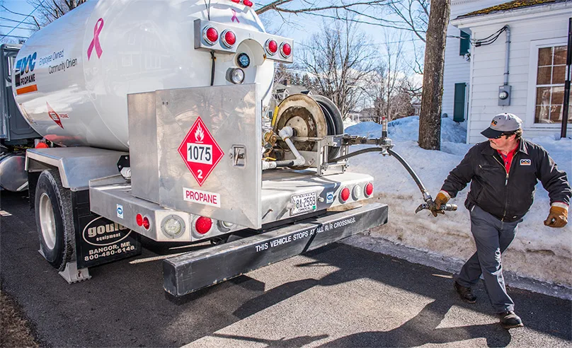 daigle employee unravels the fuel hose from the fuel bowser truck while parked on the side of the street next to a suburban house