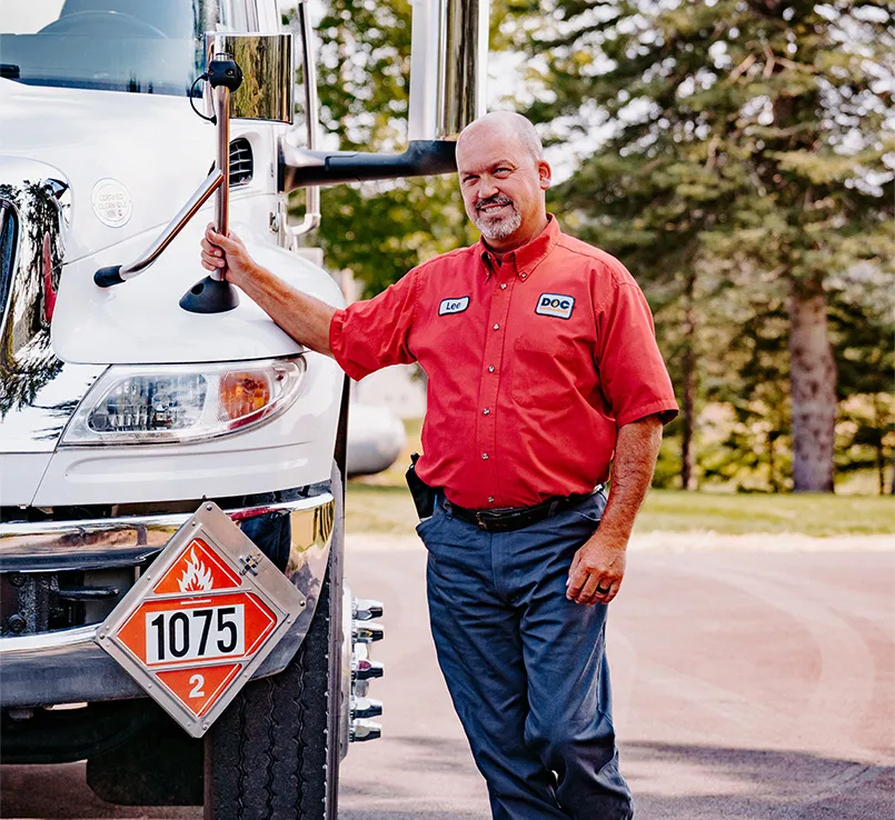 Daigle employee in his work uniform leaning against his truck