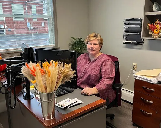 a woman sitting behind her desk in a small office
