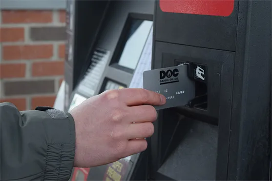 man inserting his DOC charge card into a gas pump card slot