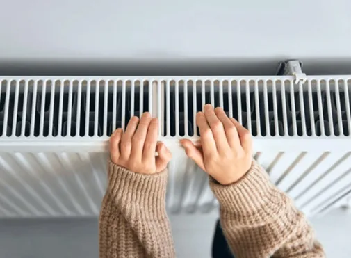 the hands and forearms of a young girl showing her warming her hands on a heater
