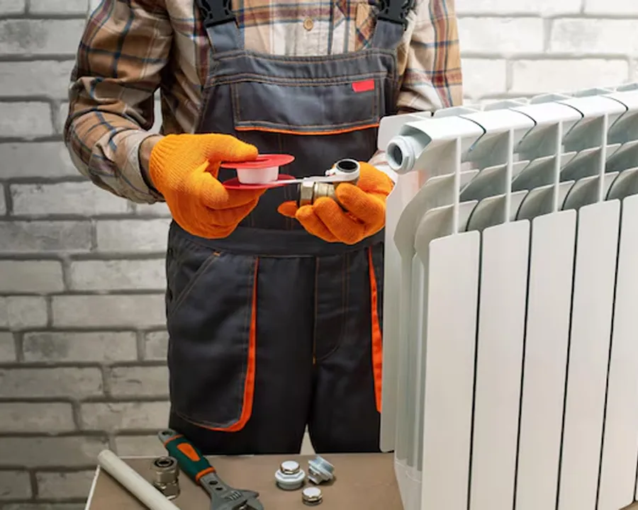 man in safety gear working on a heater that sits on a small table
