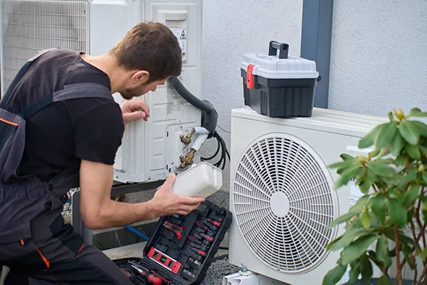 man performs maintenance on an outdoor AC unit