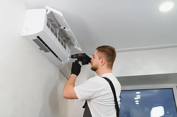 man in work gear performing maintenance on minisplit
