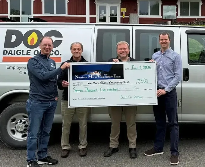 daigle team holding a check for charity while standing next to their work van