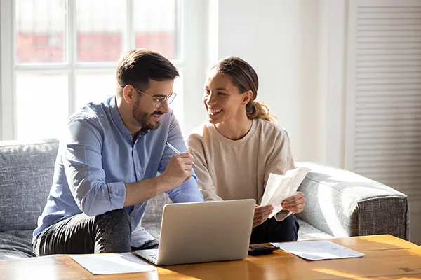 well-dressed young couple working together jovially with paperwork and a laptop in front of them