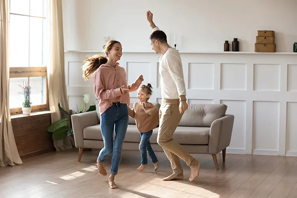 young couple and their daughter dancing in their living room