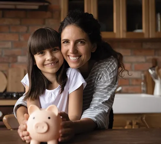 mom and daughter standing in their kitchen holding a piggy bank together