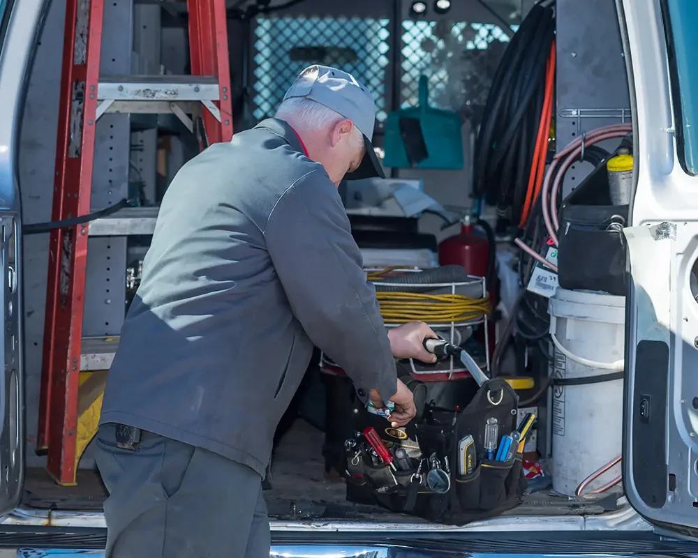 maintenance worker grabbing his toolbox out of the back of a work vehicle.