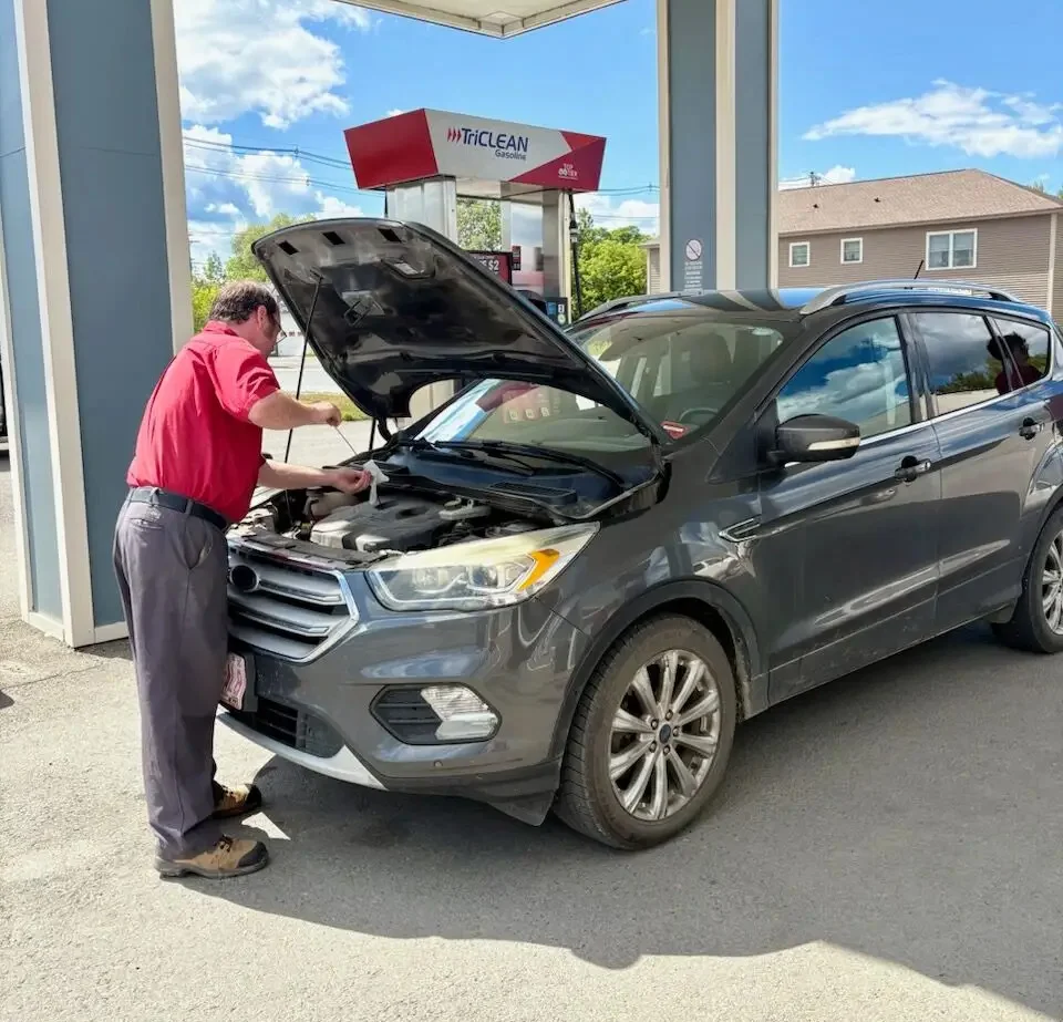 daigle attendant checking the oil for a customer parked at the gas pump